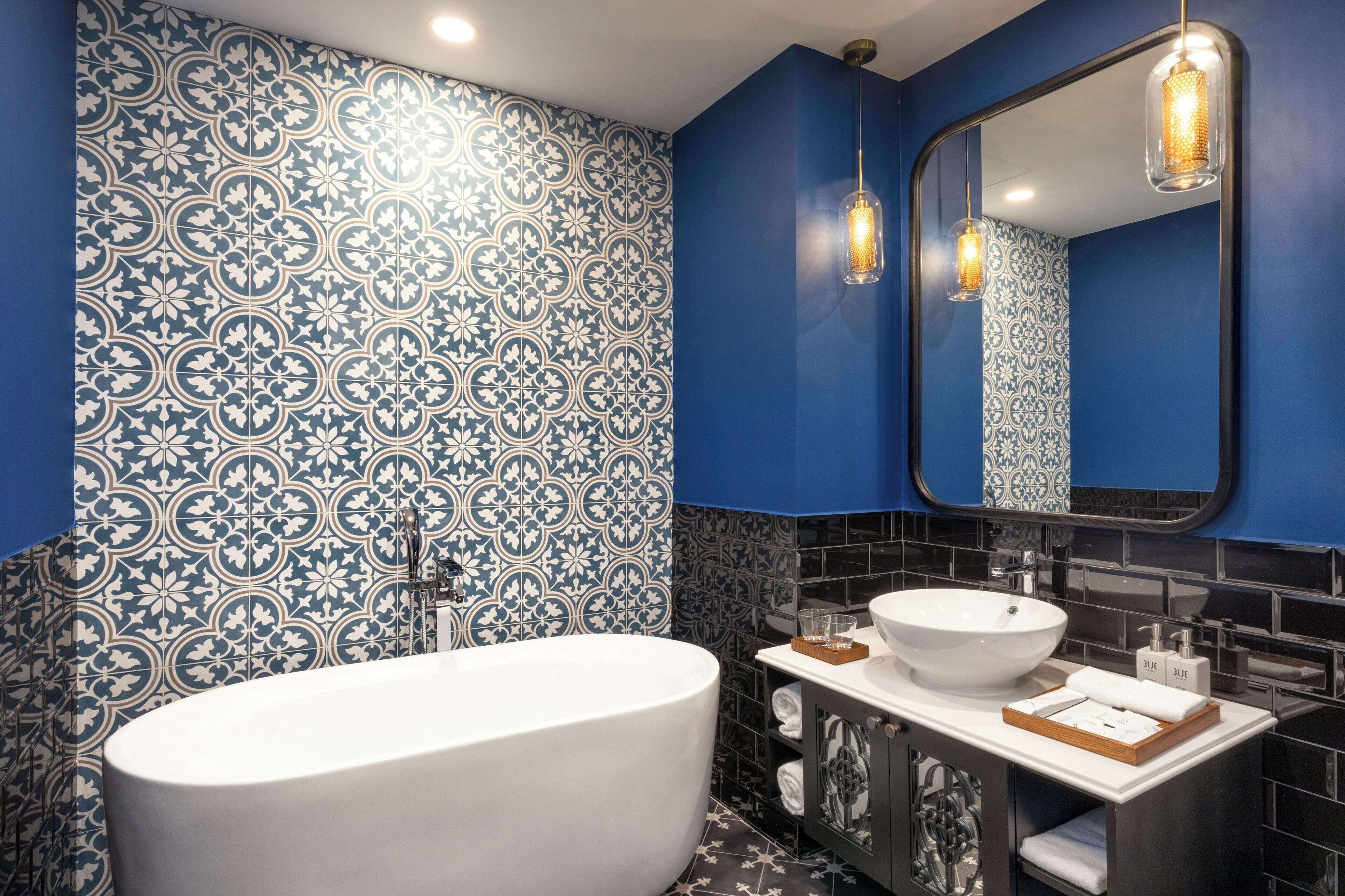 A modern bathroom with a freestanding bathtub, a vanity with a white sink, and a large mirror.