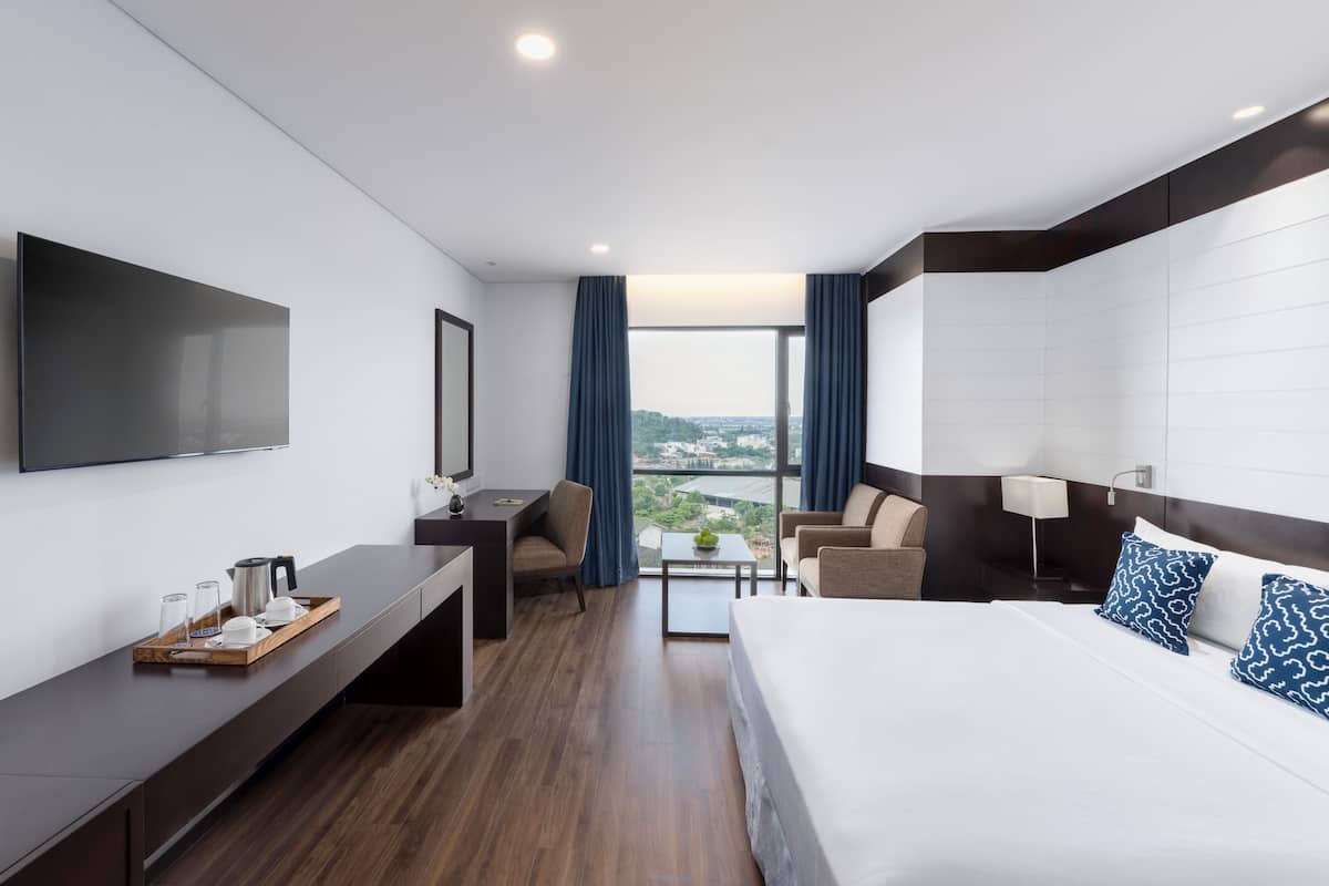 Een moderne hotelkamer met een groot bed, een bureau en een televisie.