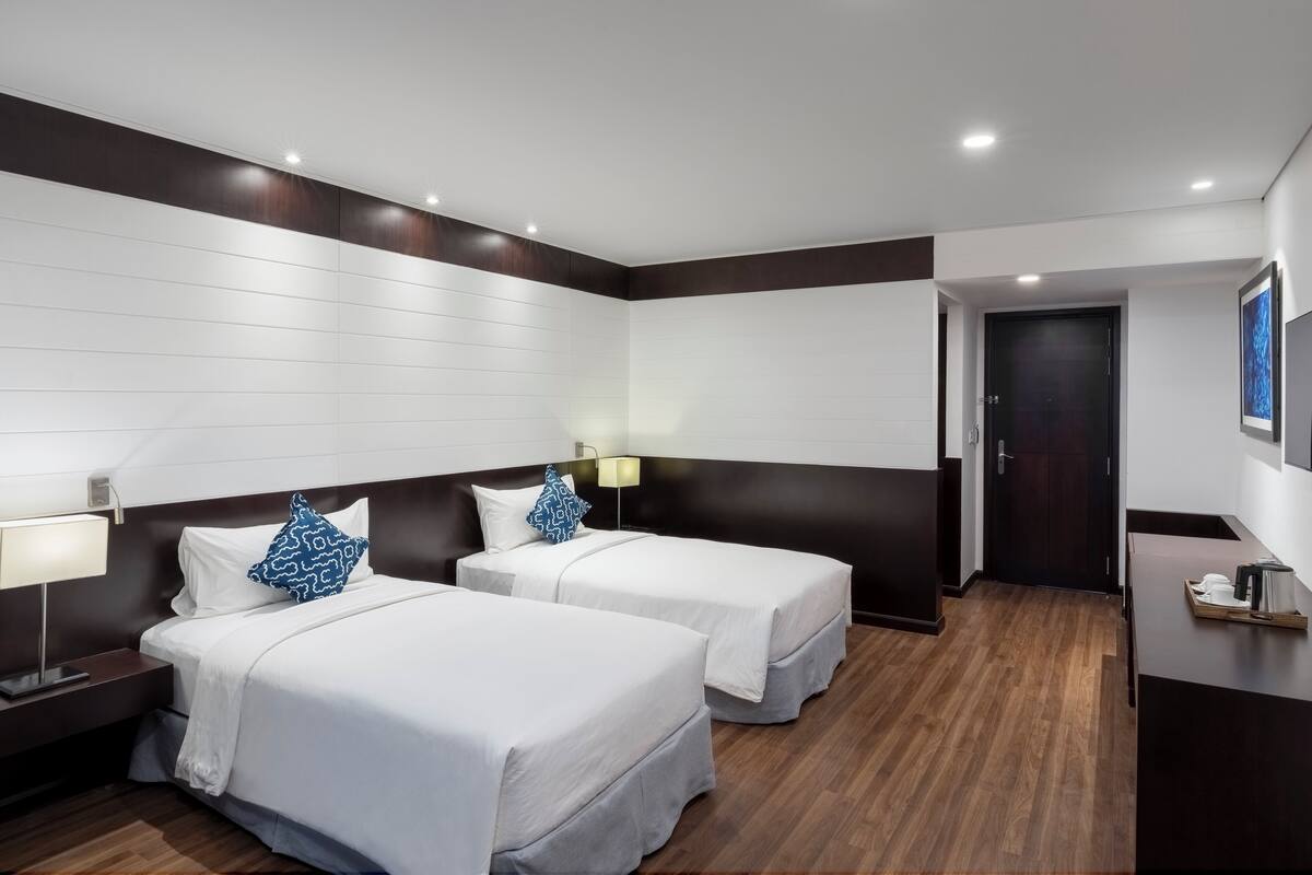 Een hotelkamer met twee bedden, een bureau, een lamp en een deur naar een badkamer.