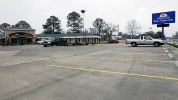 A parking lot with several vehicles, a building with a sign for 'Americas Best Value Inn', and a clear sky.