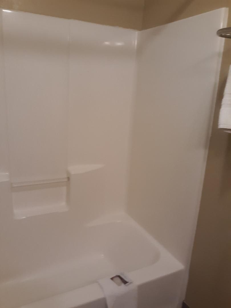 A bathroom with a white bathtub, a shower area, and a towel rack.