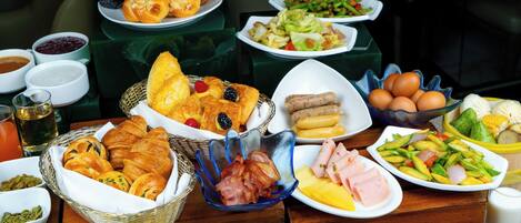 A buffet with various dishes including bread, meats, vegetables, and fruits.