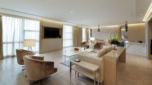 Een moderne woonkamer met een bank, fauteuils, een salontafel en een televisie.