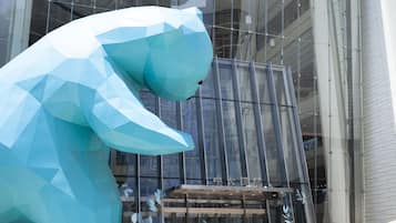 A large, geometric sculpture of a bear in front of a modern building with glass windows.