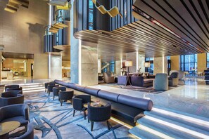A spacious lobby with a long bench, seating area, and modern lighting fixtures. - Hilton Xi'an High-tech Zone (Xi'an)