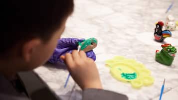 A child painting on a surface with paintbrushes and a palette.