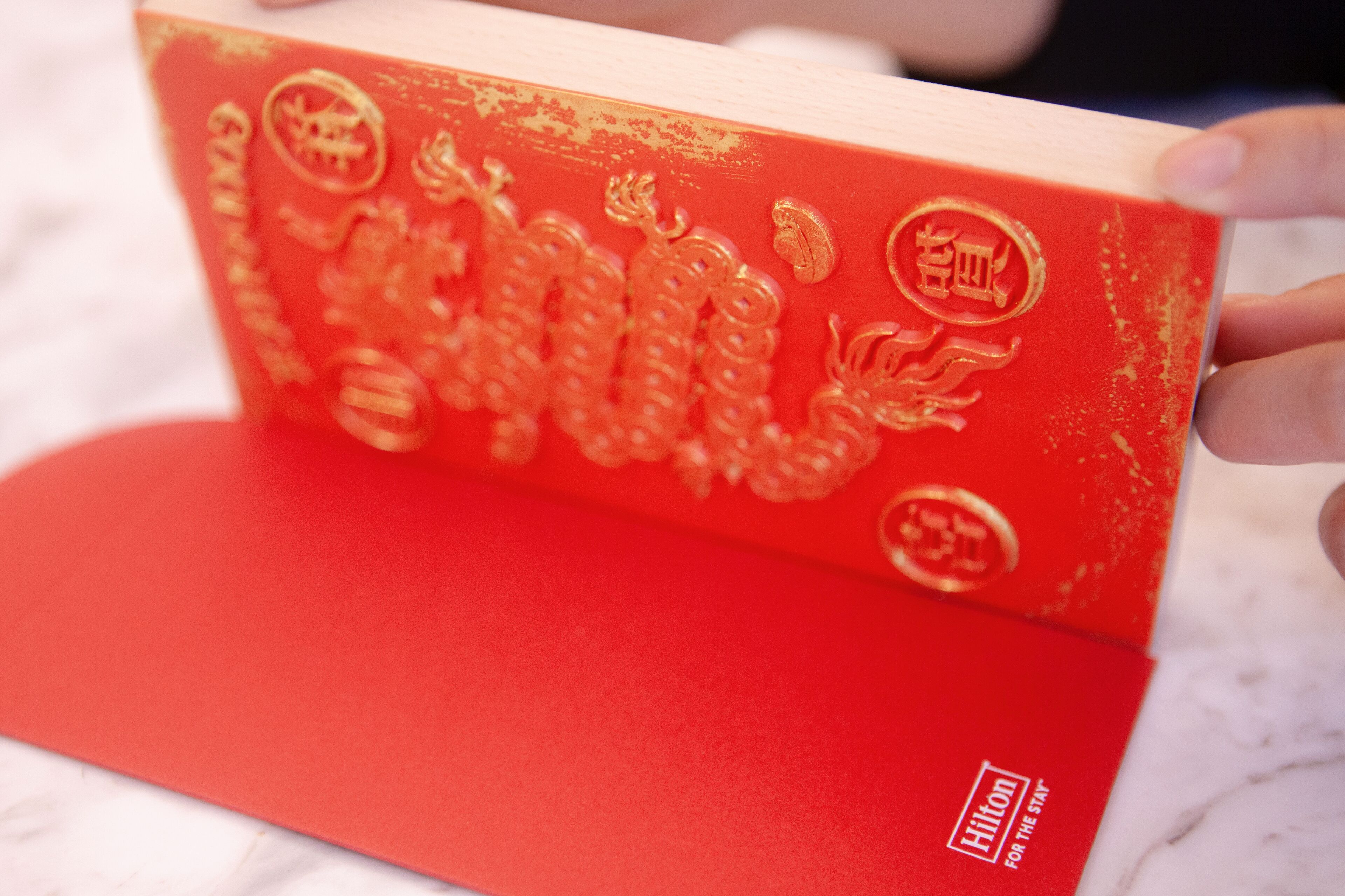 A red book with gold embossed Chinese characters and the Hilton logo.