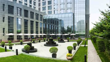A modern building with a courtyard featuring outdoor seating, potted plants, and a central water feature.