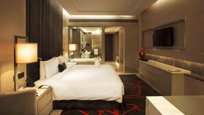 Hotelkamer met een groot bed, nachtkastjes, een televisie, een spiegel en een badkamer die door een open deur zichtbaar is.