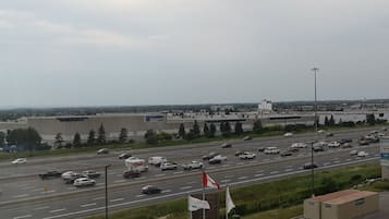 Una autopista con múltiples carriles y vehículos, incluyendo automóviles y camiones. Se observan edificios industriales y un almacén grande al fondo.