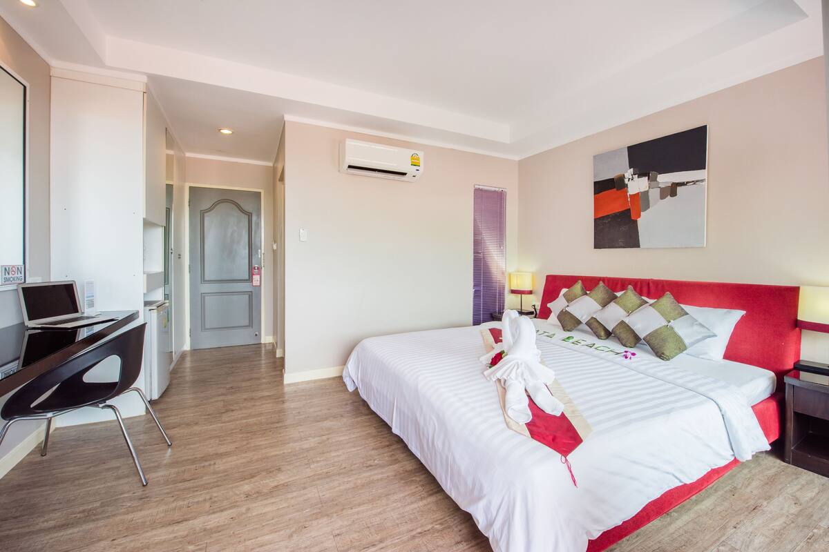 A hotel room with a bed, a desk, and a computer.