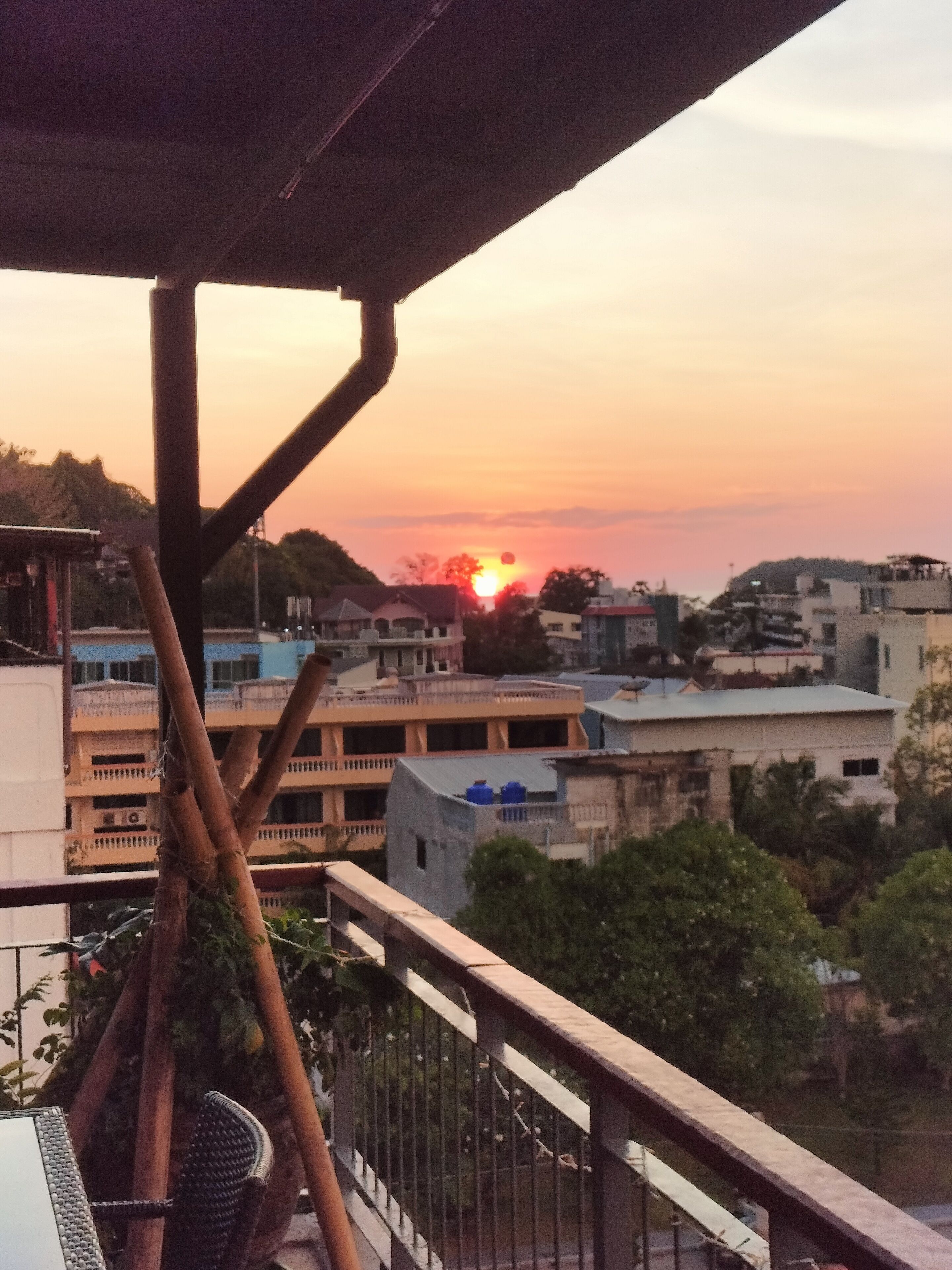 A balcony with a view of a sunset over a cityscape.