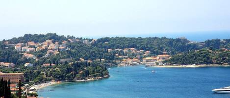 A coastal town with buildings along the shoreline, a marina, and a clear view of the sea.