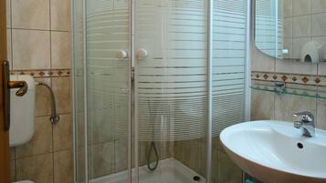 A bathroom with a glass-enclosed shower, a sink, and a toilet.