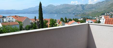 A balcony with a view of a lake, mountains, and residential buildings.