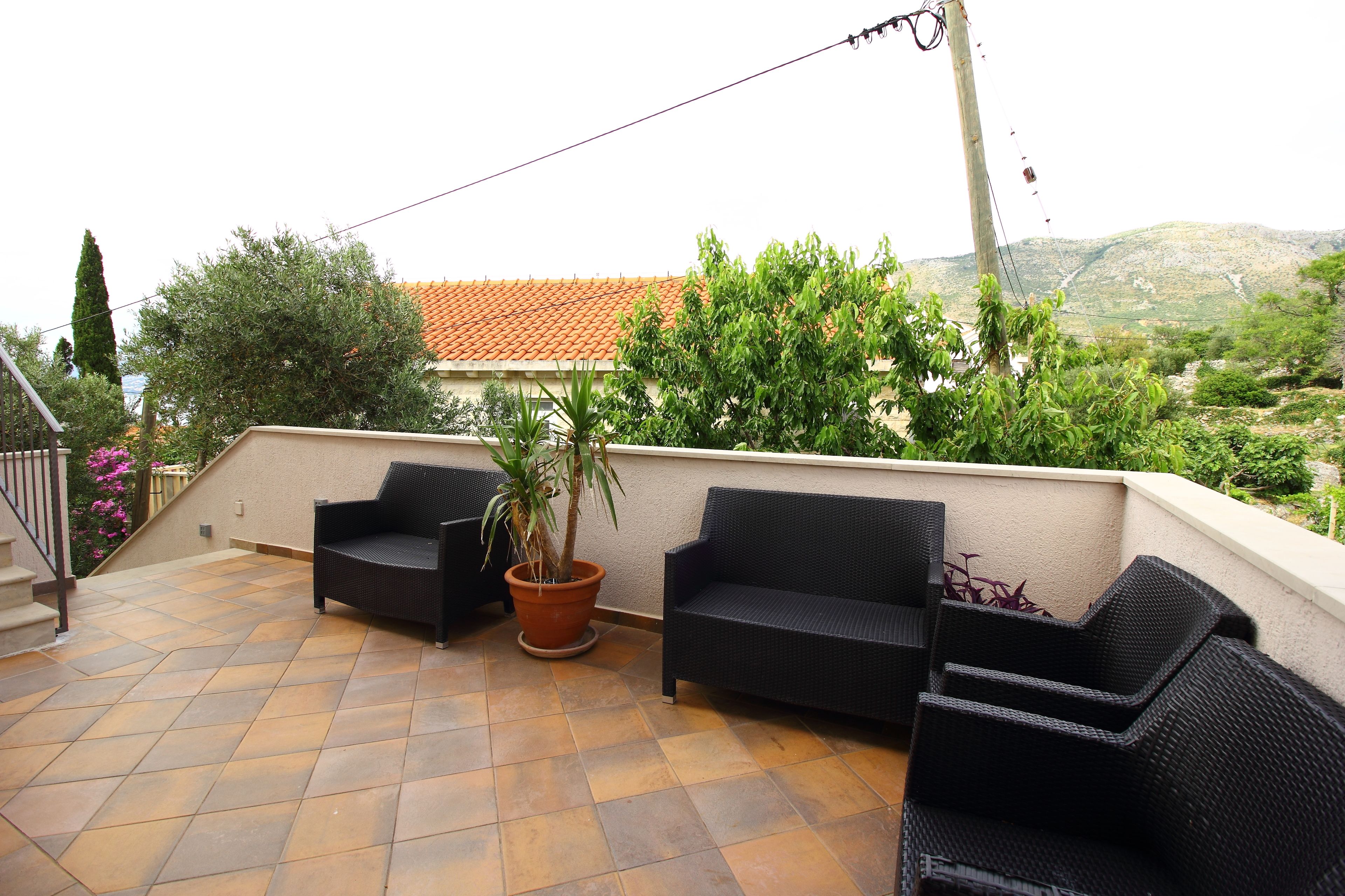 Un patio con muebles de exterior, una planta en maceta y vistas a una colina.