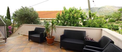 Un patio con muebles de exterior, una planta en maceta y vistas a una colina.