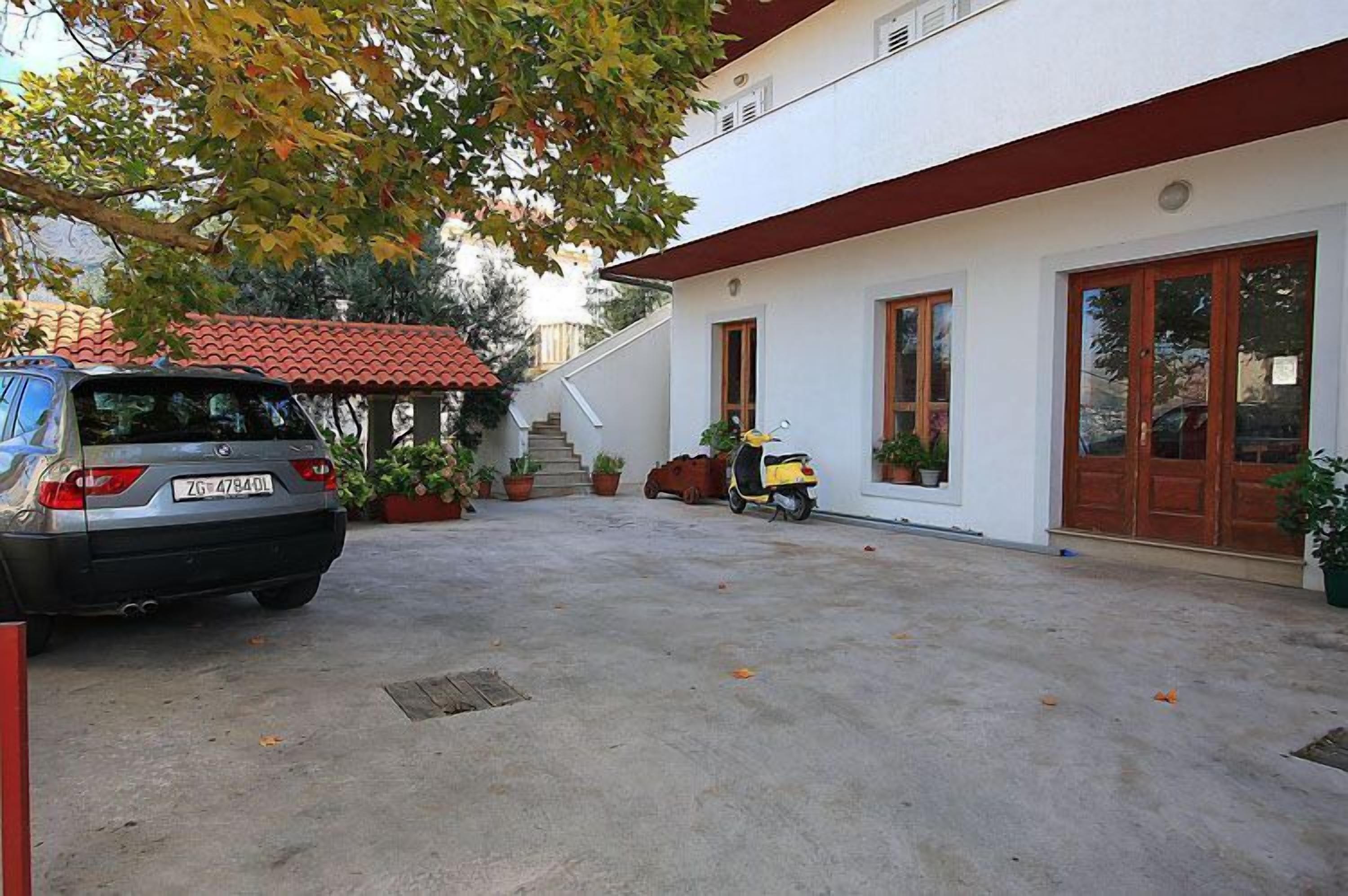 A building with a red-tiled roof, a parked car, and a scooter.
