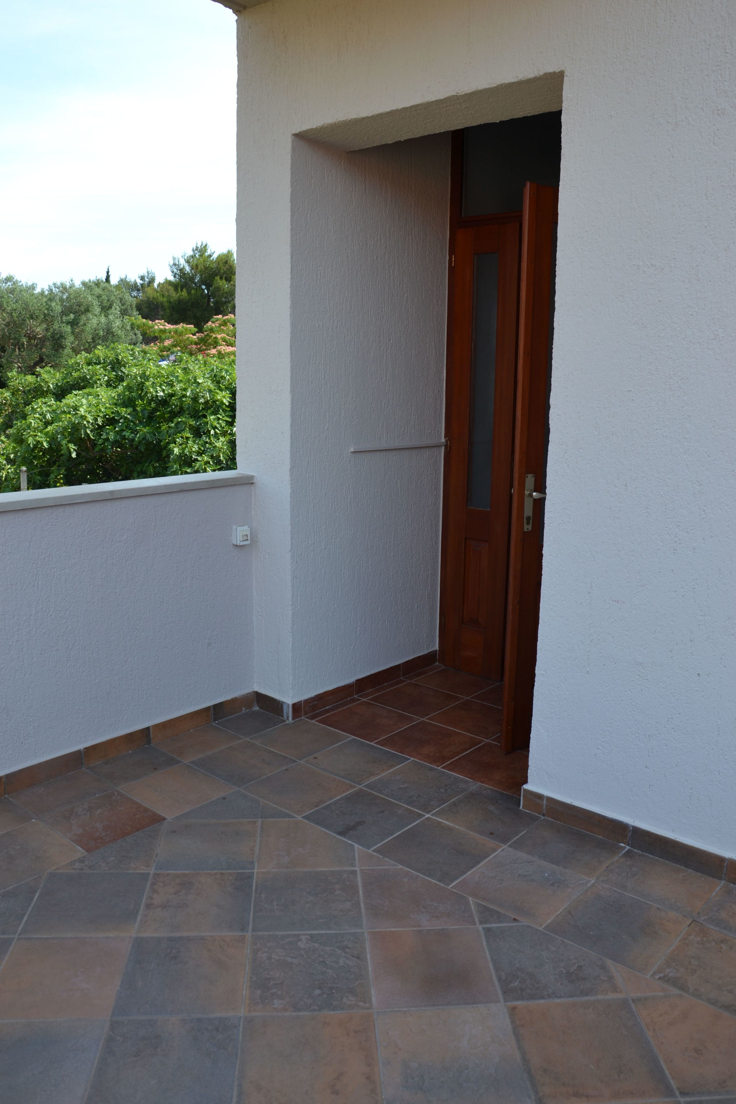 Un petit balcon fermé, doté d’un sol carrelé et d’une porte en bois.