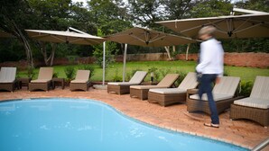 A poolside area with lounge chairs and umbrellas. - Ursula's Homestead (Victoria Falls)