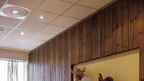 Una sala de estar moderna con chimenea, paneles de madera en las paredes y una lámpara de pie amarilla.