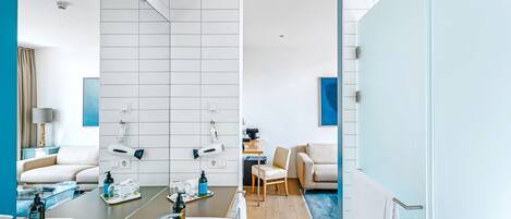 A modern bathroom with a large mirror, a bathtub, and a vanity with toiletries.