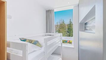Habitación con literas y ventana con vista a un paisaje verde.