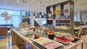 Un área de bufé con diferentes opciones de comida y una zona de estar con sillas y mesas.
