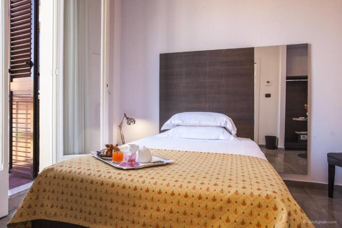 A hotel room with a bed, a tray with breakfast items, and a view of the outside.