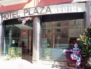 Exterior de un hotel llamado "Plaza Inn" con un gran letrero sobre la entrada.