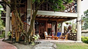 Un espace extérieur aménagé, abrité et doté de chaises et de tables, un sentier en pierre et un escalier menant à un niveau supérieur.