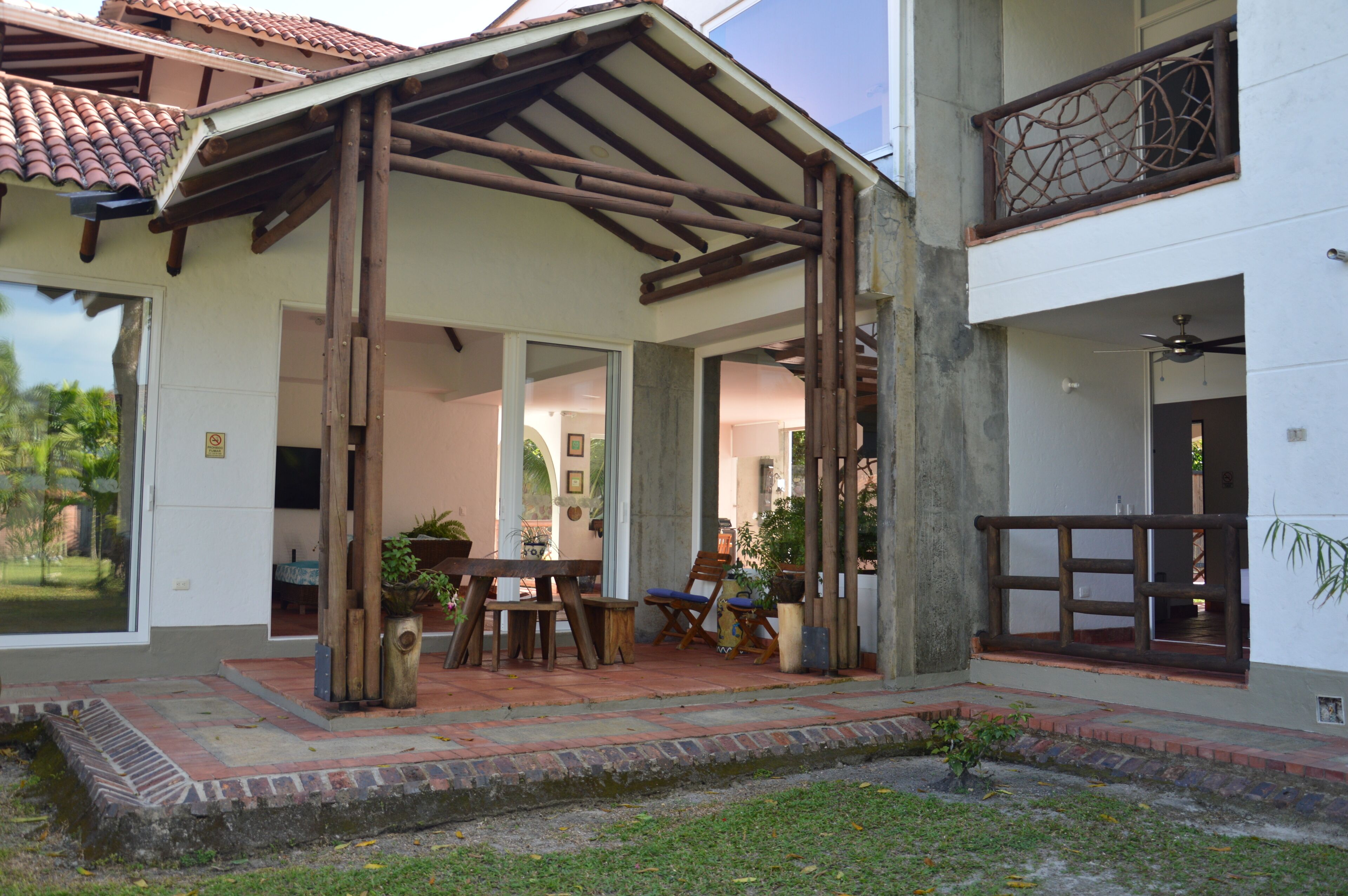 A covered outdoor area with a patio, wooden furniture, and potted plants.