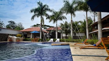 Una piscina al aire libre, sombrillas, sillones reclinables de piscina