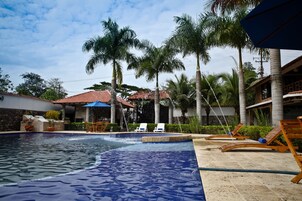 Una piscina al aire libre, sombrillas, sillones reclinables de piscina