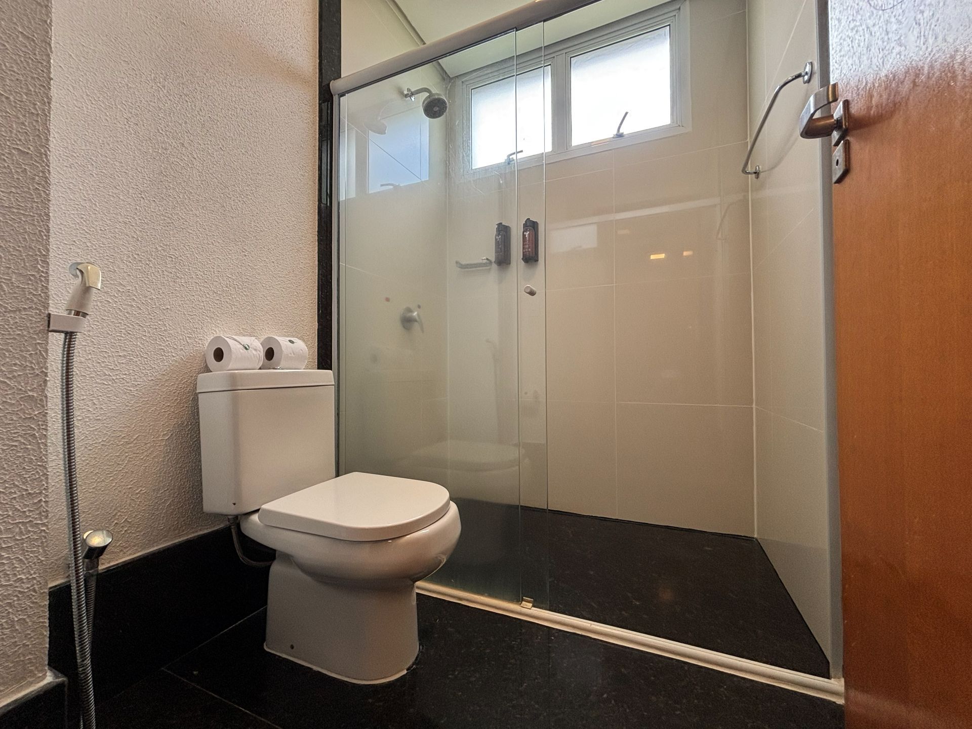 Un baño con inodoro, cabina de ducha de vidrio y un perchero para toallas.