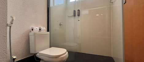 Un baño con inodoro, cabina de ducha de vidrio y un perchero para toallas.