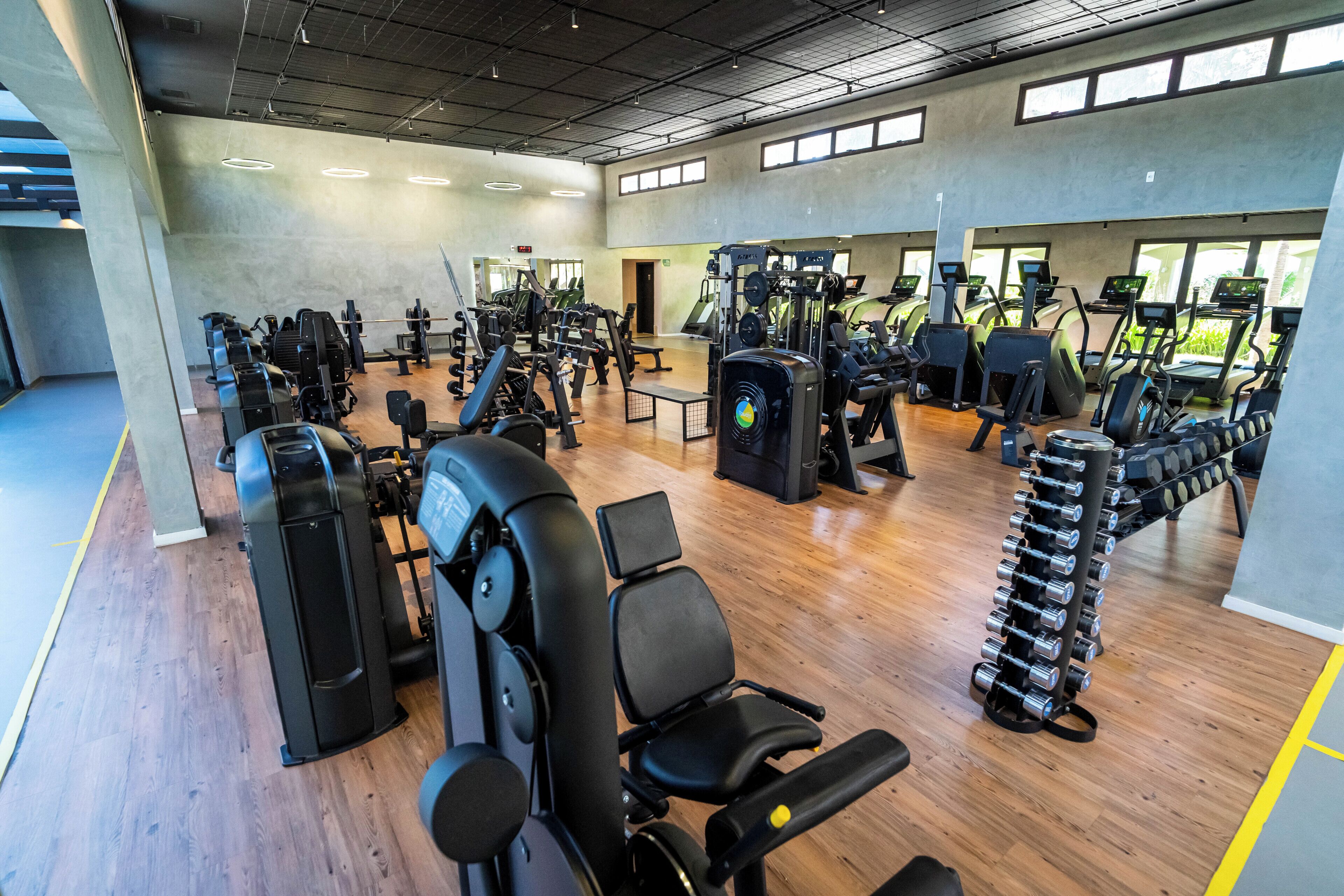 Un gimnasio con diversas máquinas de ejercicio, cintas de correr y estantes para pesas.