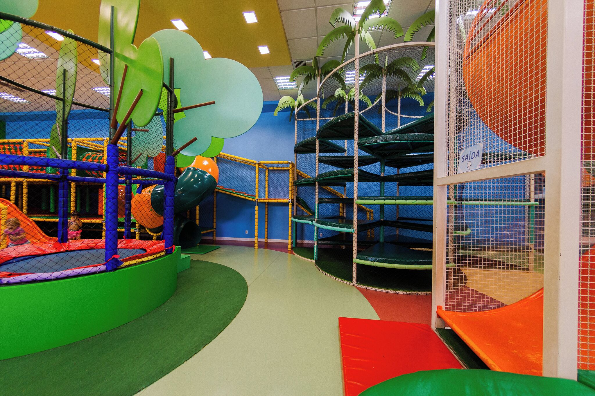 Espaço de recreação infantil com diversas estruturas de lazer, incluindo uma rede de escalada e um escorregador.