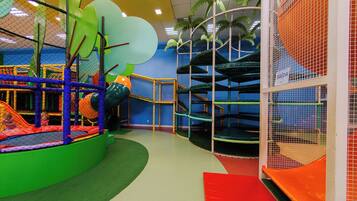 Espaço de recreação infantil com diversas estruturas de lazer, incluindo uma rede de escalada e um escorregador.