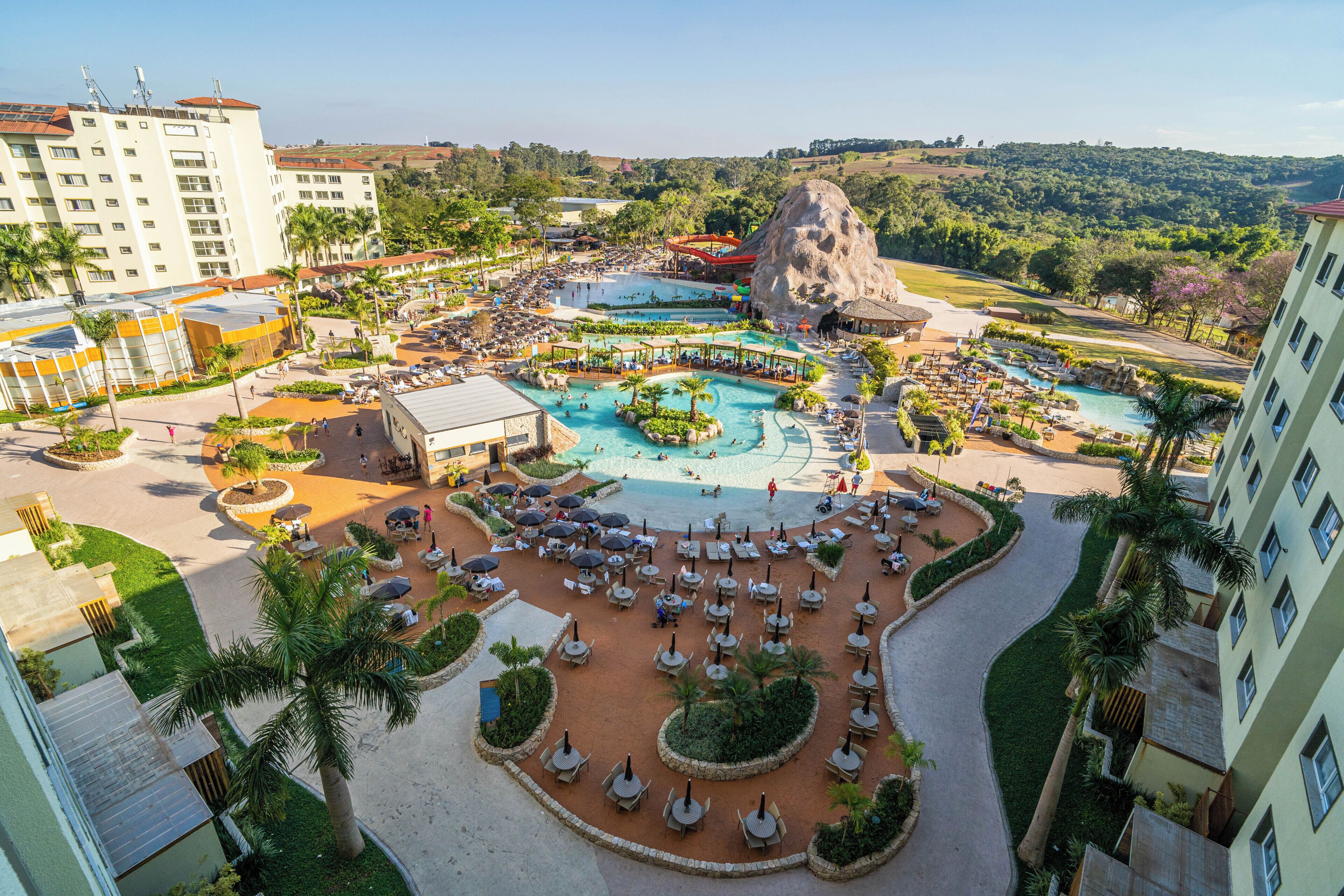 Un resort con varias piscinas, una gran formación rocosa y diversas zonas de estar al aire libre.