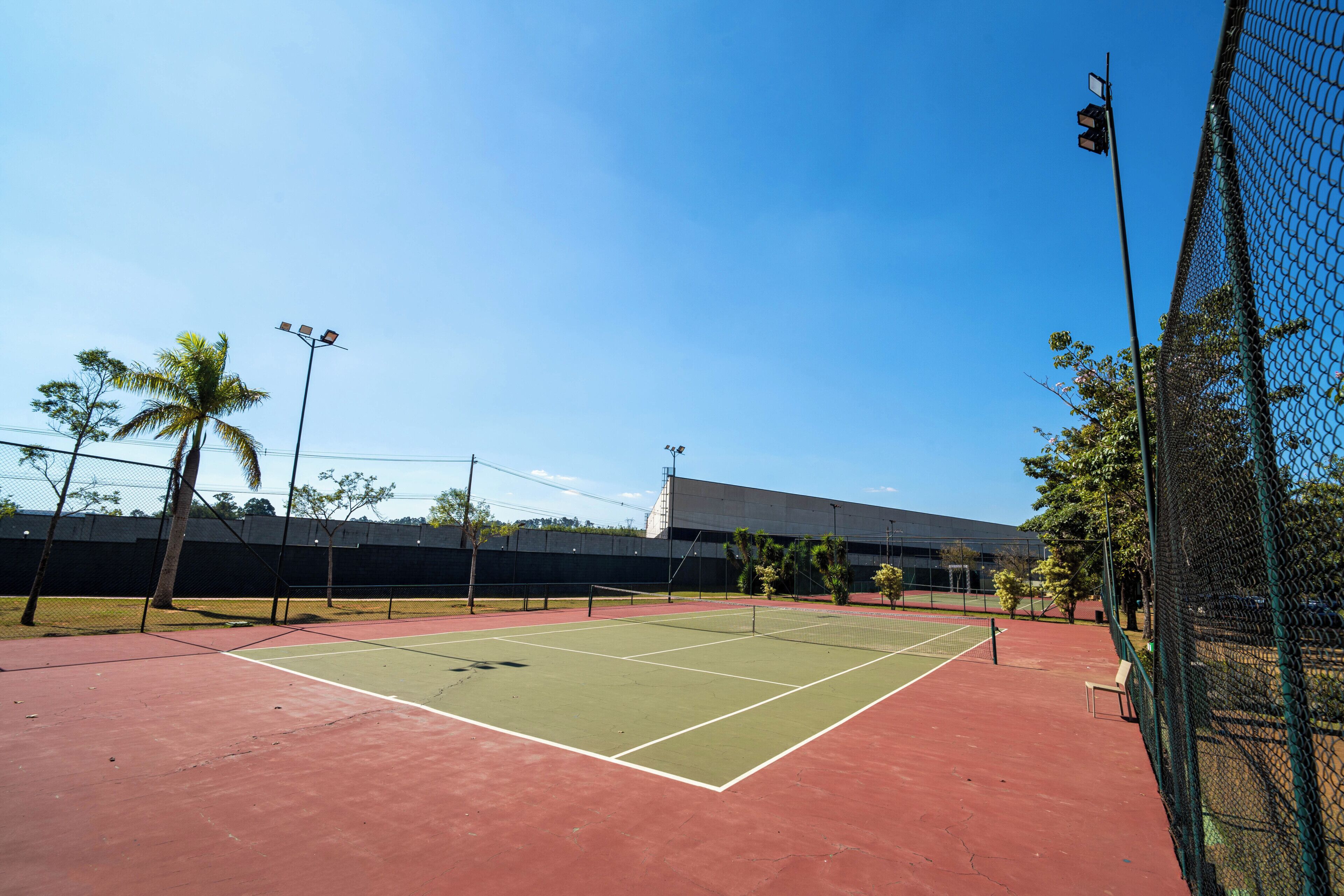 A tennis court with a net, a bench, and a fence.