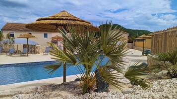 Una piscina al aire libre, sillones reclinables de piscina