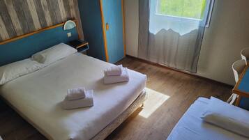 Quarto de hotel com cama, mesa de cabeceira e uma cadeira.