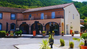 Un hotel con un patio central, mobiliario exterior y montañas al fondo.