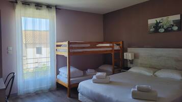 A bedroom with a bunk bed, a single bed, a window with sheer curtains, a wall-mounted lamp, and a painting.