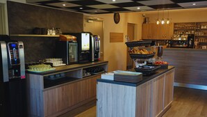 Un área de bufé con una máquina de café, un refrigerador y diferentes opciones de comida.