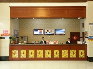 Un comptoir d’accueil doté de deux écrans, d’un panneau décoratif en bois et d’un emblème rouge sur la porte.