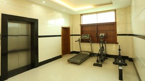 Sala de ginástica com esteira, elíptico e bicicleta ergométrica.