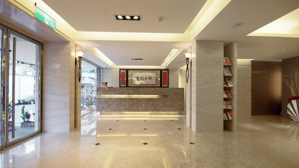 A modern hotel lobby with a marble floor, a reception desk, and a staircase leading to an upper floor. - The Metro Hotel (Taipei)