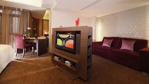 A hotel room with a bed, a desk, a television, a red sofa, and a patterned carpet. - The Metro Hotel (Taipei)